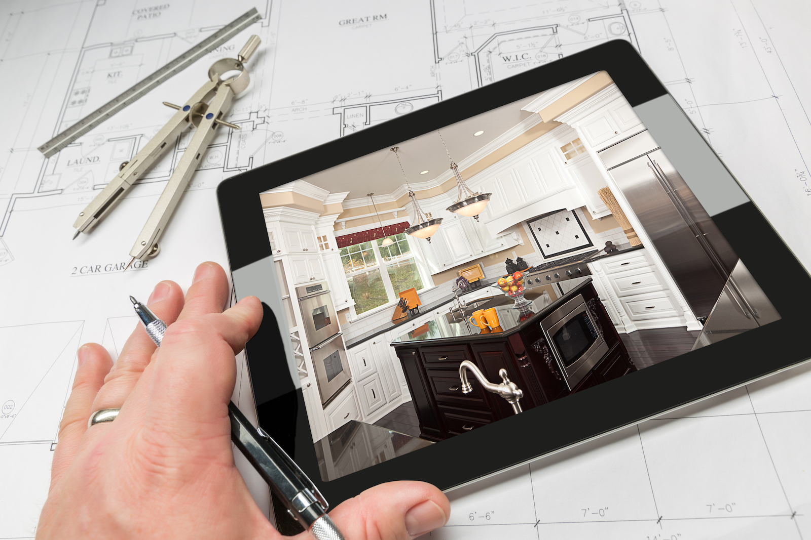 Hand of Architect on Computer Tablet Showing Custom Kitchen Photo Over House Plans, Compass and Ruler.